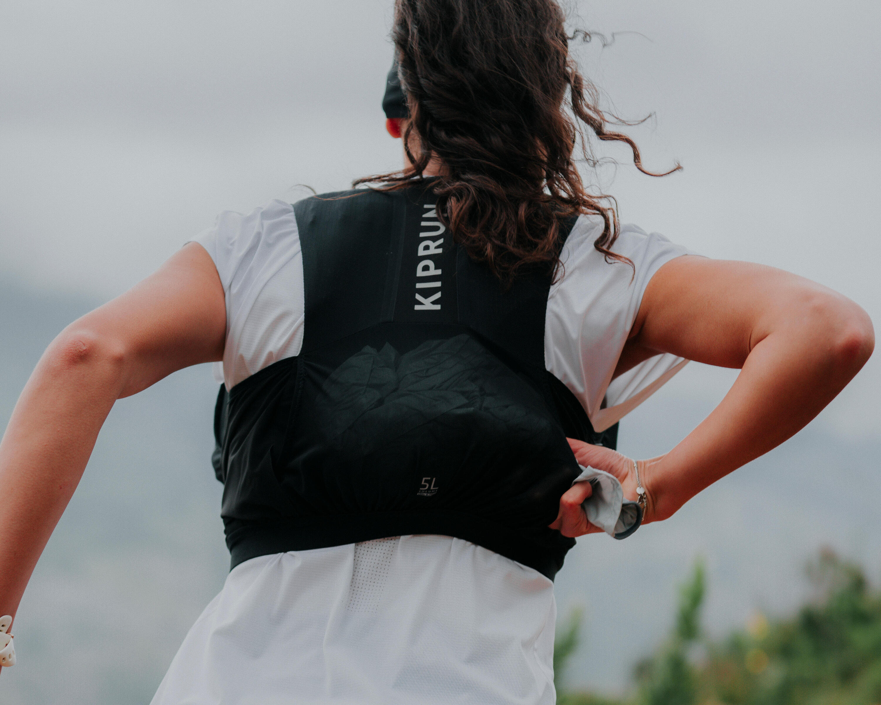 Runner from behind adjusting a black Kiprun 5L trail running hydration vest