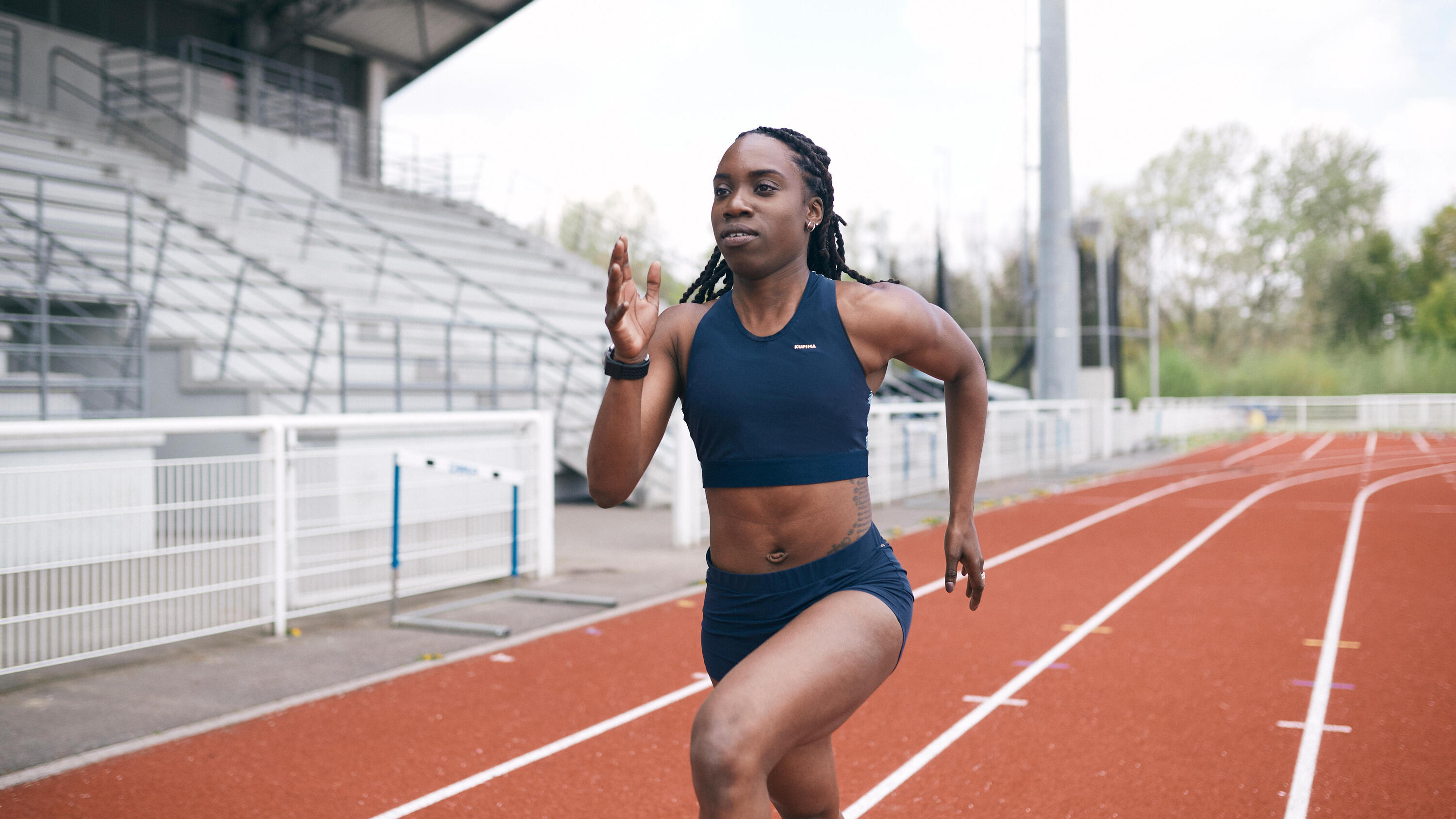 Woman sprinting on an athletics track in a navy crop top and shorts